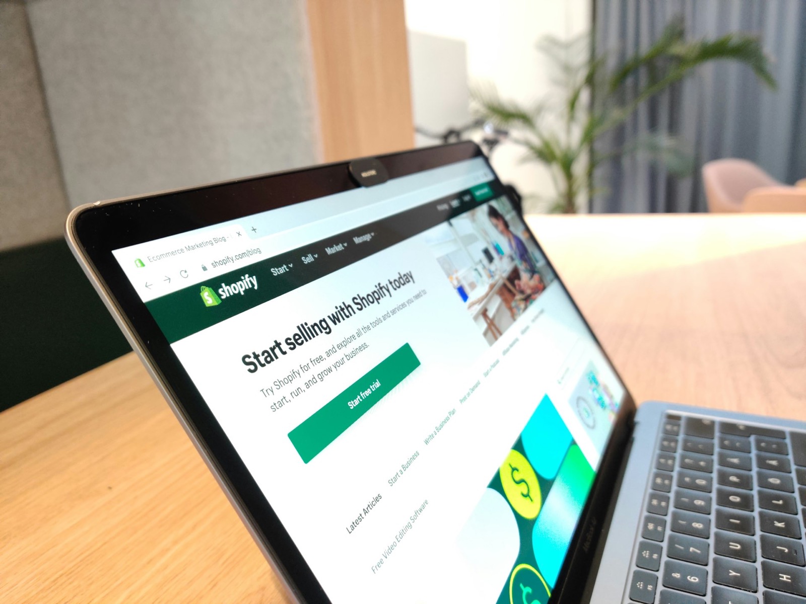 Laptop displaying the Shopify homepage: "Start selling with Shopify today" and "Start your free trial."